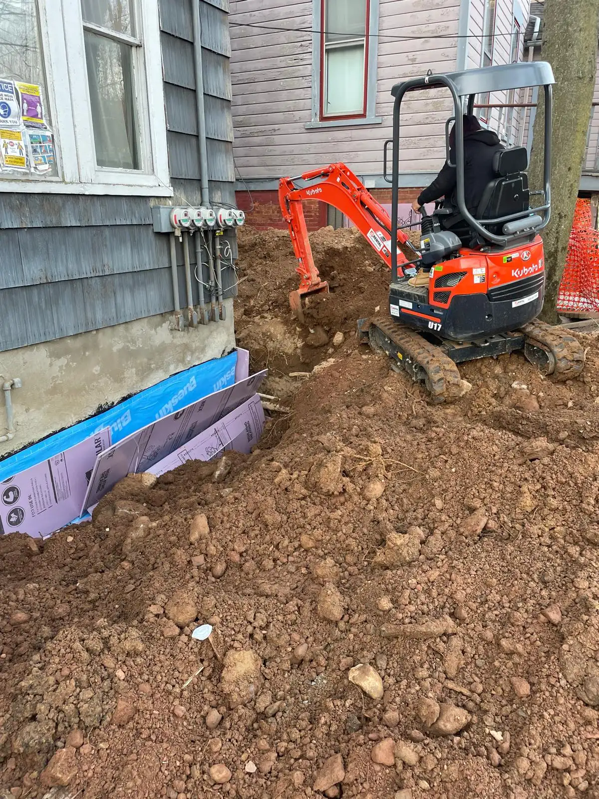 Mini excavator digging along foundation — Stapleton, Staten Island